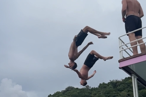 Two men do a backflip of a boat into the sea
